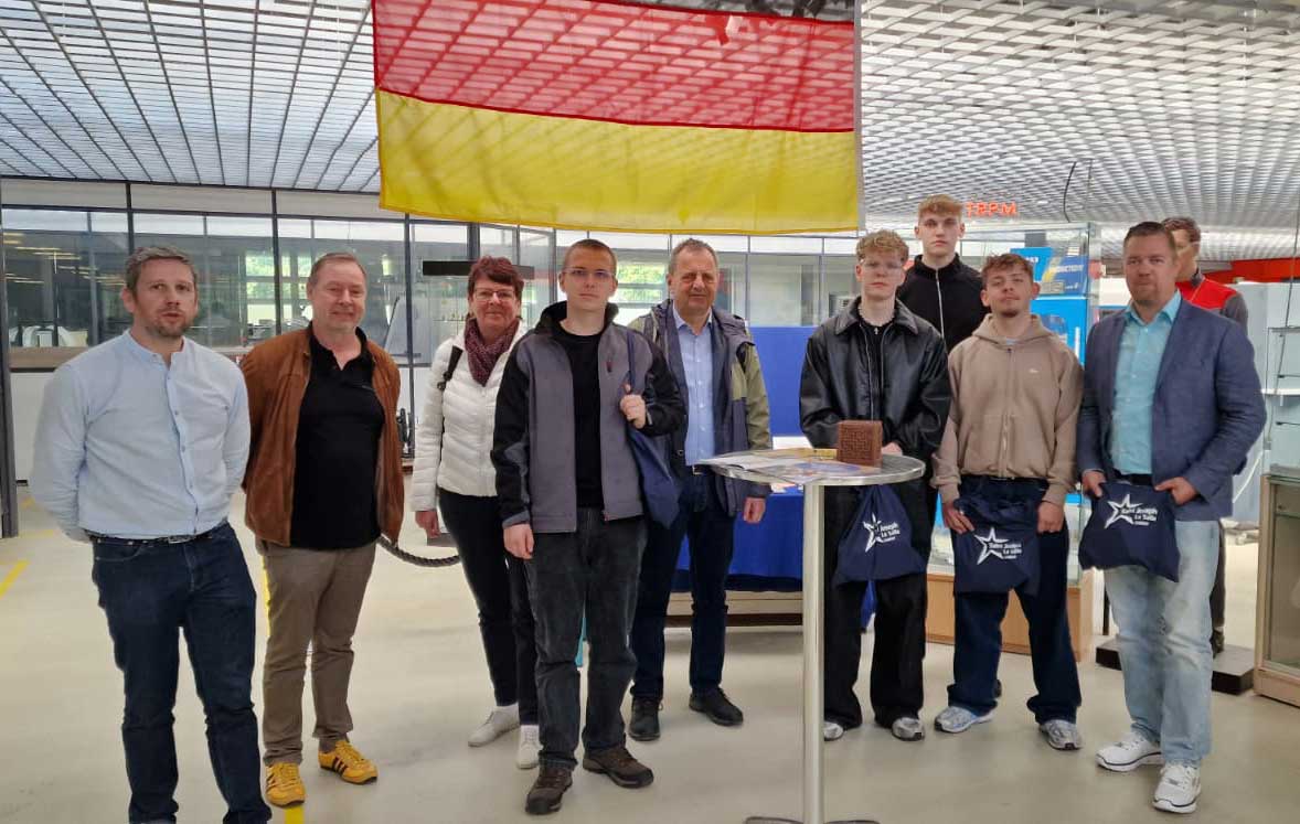 Deutsche Besucher und französische Betreuer bei einem Gruppenbild in der französischen Schule. Von der Decke hängt eine Deutsche Flagge.