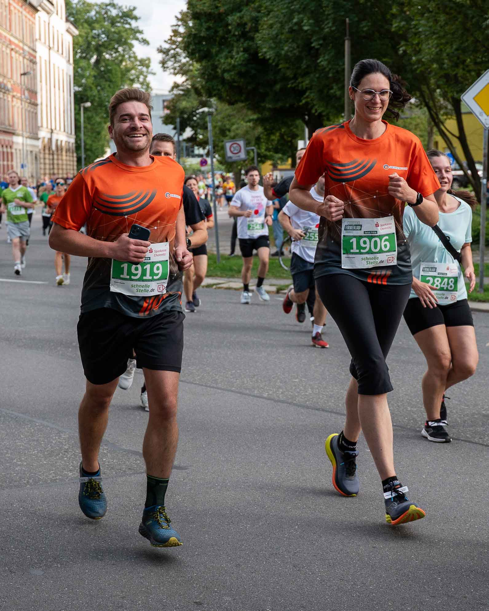 Ein Mitarbeiter und eine Mitarbeiterin von Sachsen Guss laufen beim Firmenlauf Chemnitz 2026. Der Mitarbeiter lacht dabei in die Kamera.