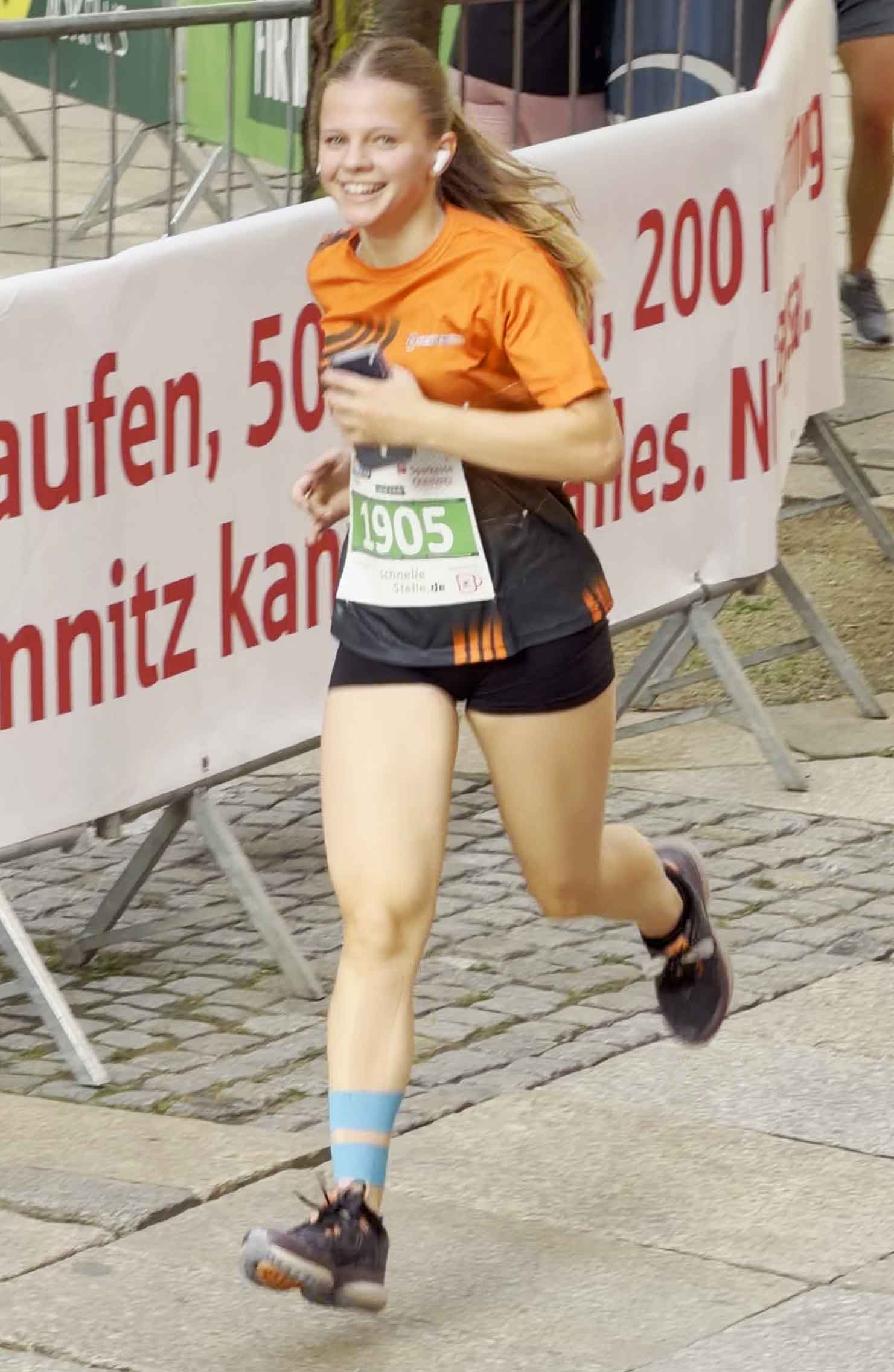 Ein weibliches Teammitglied von Sachsen Guss läuft beim Firmenlauf Chemnitz 2026. Sie lacht in die Kamera.