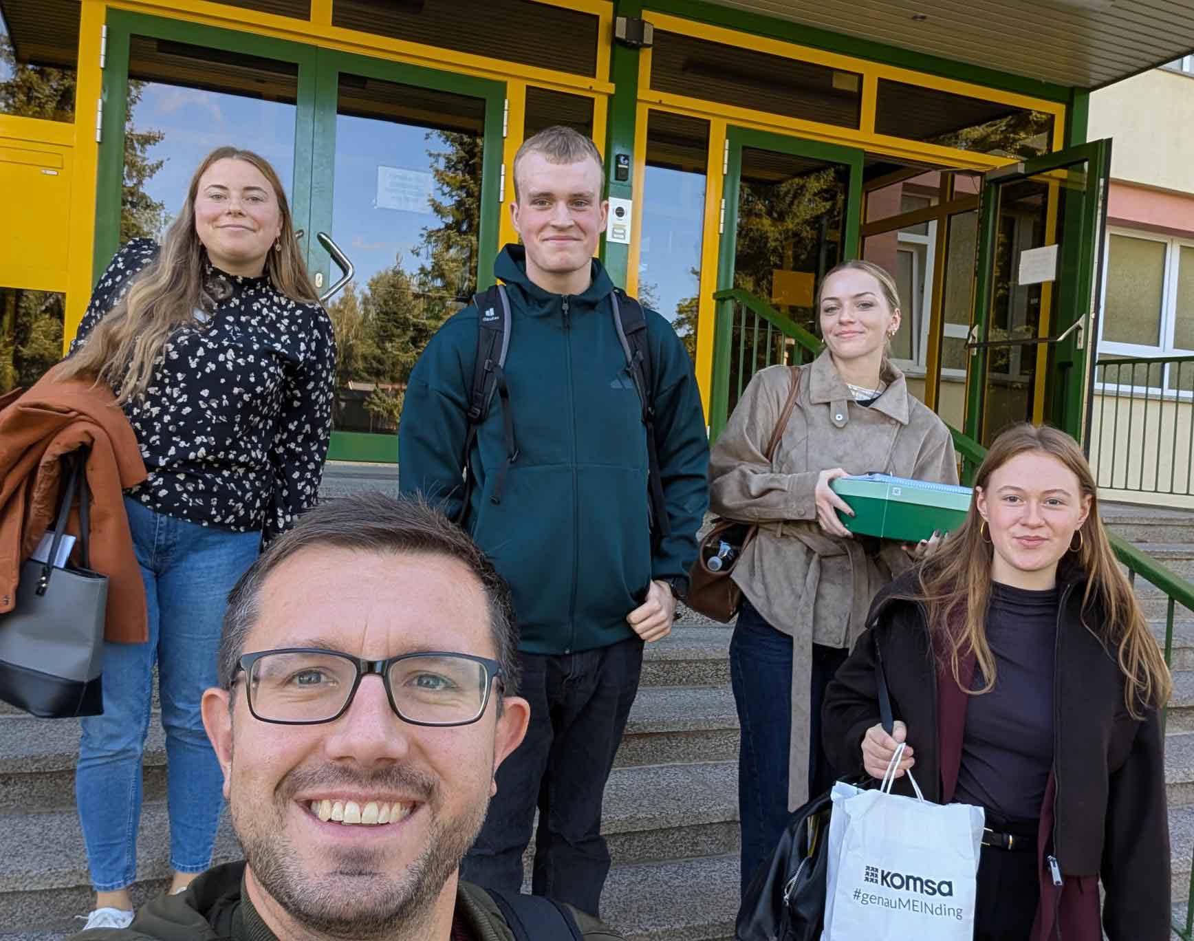 Lukas Hofmann steht mit weiteren Azubibotschaftern und Azubibotschafterinnen auf der Außentreppe eines Schulgebäudes. Sie schauen in die Kamera.